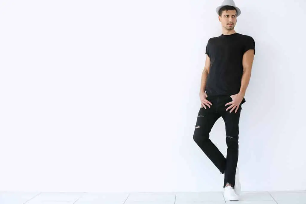 Handsome stylish young wearing skinny jeansman posing on light background