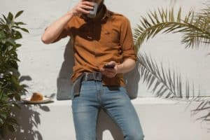 hipster guy wearing skinny jeans using his smart phone outdoors