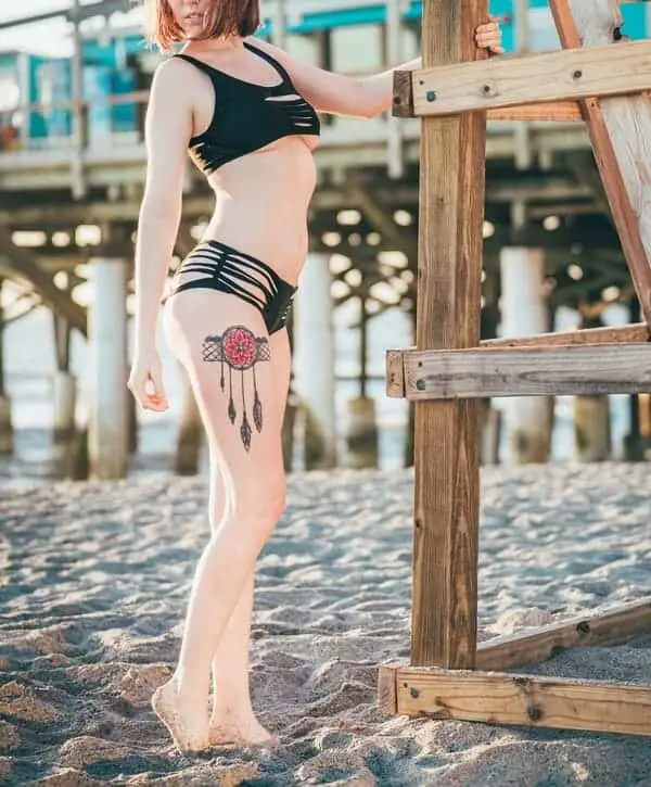 a woman in black underboob bikini standing on gray sand