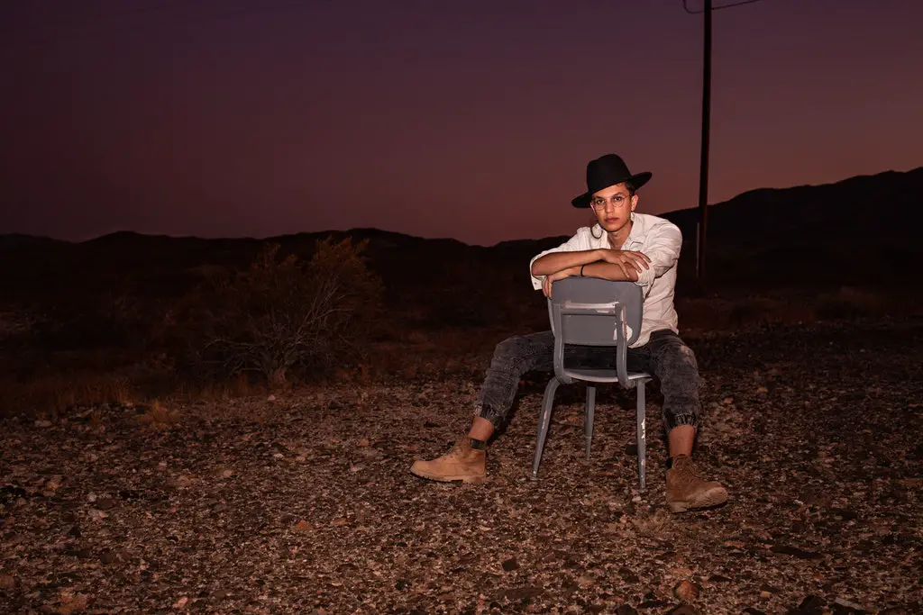 man in white shirt and black pants -sitting-backward-on-chair-